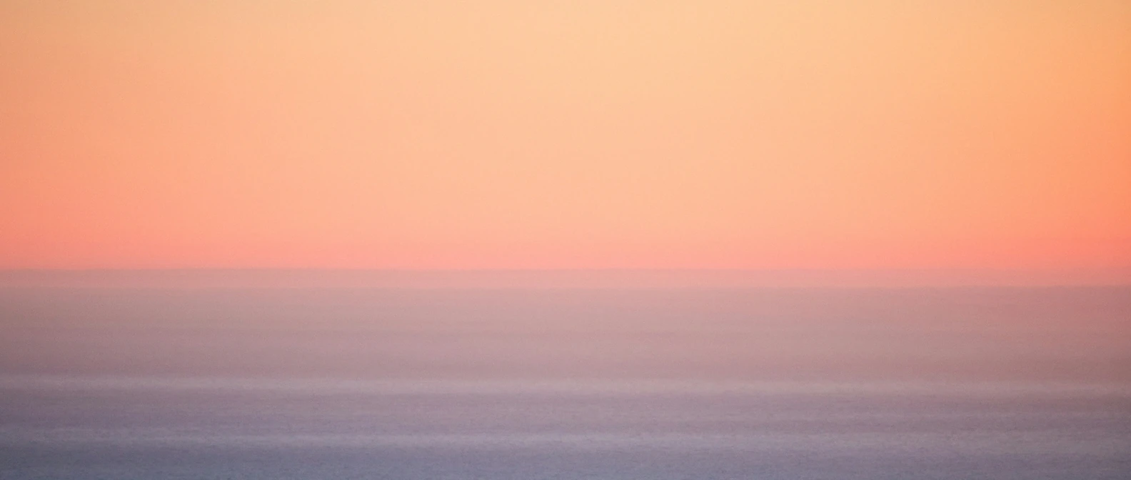 Warm sunset light glowing over a calm ocean horizon